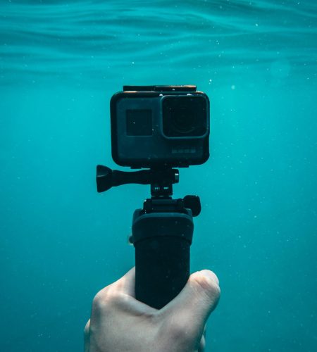 A hand holding an action camera underwater in Jezerane, Croatia.