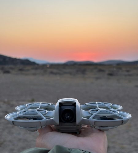 Silhouette of a drone held against a vivid sunset in a desert landscape.